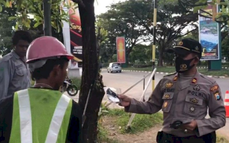 BAGI MASKER. Kapolsek Kawasan Bandara Sultan Hasanuddin Iptu Asep Widianto membagikan masker di sekitar Bandara Internasional Sultan Hasanuddin Makassar, Minggu (5/7/2020). foto: anas/pluz.id