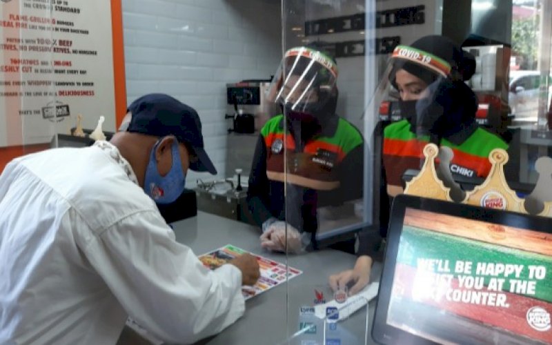 LAYANI PELANGGAN. Karyawan Burger King di Jl Sultan Hasanuddin, Makassar, tengah melayani pelanggan. Outlet ini, diresmikan Sekda Kota Makassar, M Ansar, Jumat (24/7/2020). foto: doelbeckz/pluz.id