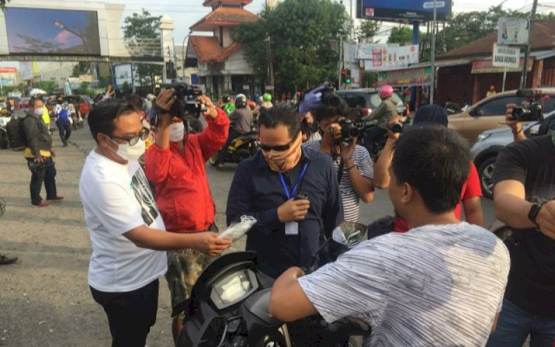 BAGI MASKER. Suasana di perbatasan Makassar-Gowa di Jl Sultan Alauddin, Jumat (17/7/2020). Nampak seorang memberikan masker gratis kepada pengendara roda dua yang tidak menggunakan masker. foto: anas/pluz.id