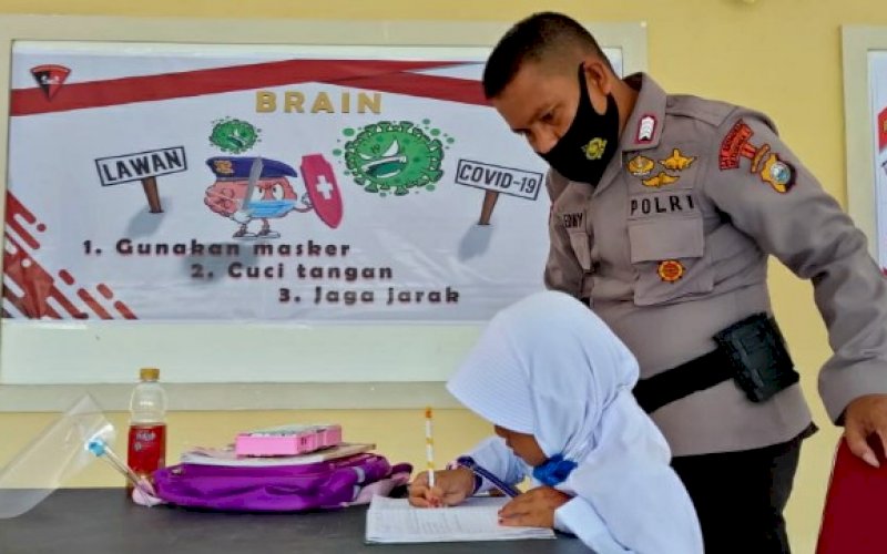 BELAJAR. Personel Batalyon C Pelopor Satbrimob Polda Sulsel menyaksikan seorang pelajar SD belajar di Aula Mako Brimob Batalyon C Pelopor di Jl MH Thamrin, Kota Watampone, Kabupaten Bone, Rabu (19/8/2020). foto: istimewa