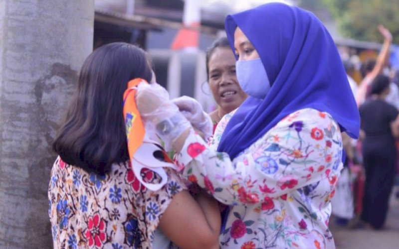PASANGKAN MASKER. Bakal calon Wakil Wali Kota Makassar, Fatmawati Rusdi, memasangkan langsung masker kepada salah satu warga yang ditemui di salah satu acara, belum lama ini. foto: istimewa