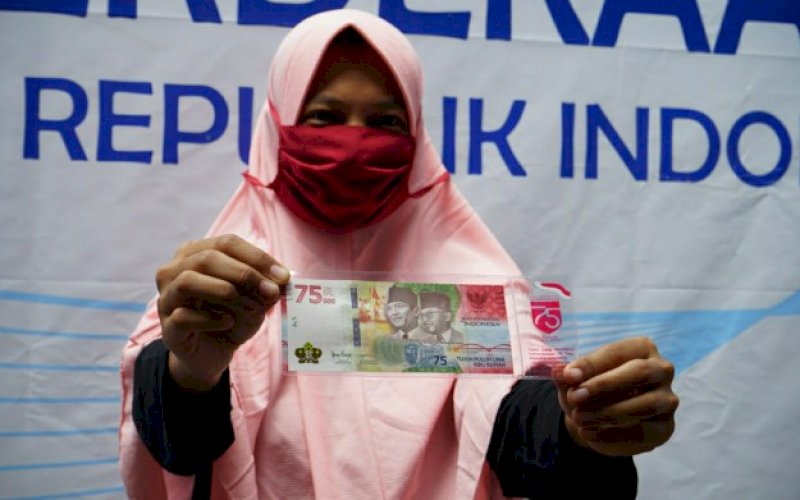 TUKAR UANG. Seorang warga memerlihatkan uang Rupiah baru berbentuk uang kertas pecahan Rp75.000 usai melakukan penukaran di Kantor Perwakilan Bank Indonesia Provinsi Sulsel di Jl Jenderal Sudirman, Kota Makassar, Selasa (18/8/2020). foto: doelbeckz/pluz.id