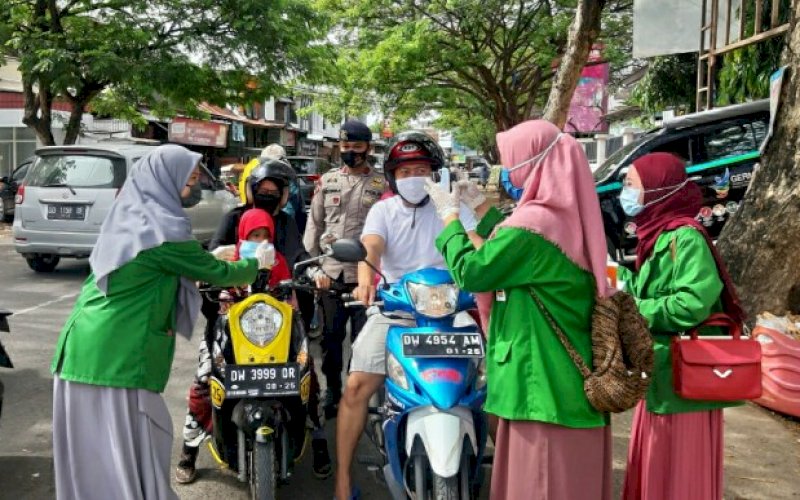 BAGI MASKER. Personel Batalyon C Pelopor Satbrimob Polda Sulsel bersama mahasiswa IAIN Kabupaten Bone menggelar kegiatan bagi-bagi masker gratis kepada para pengguna jalan di Kota Watampone, Selasa (29/9/2020). foto: istimewa