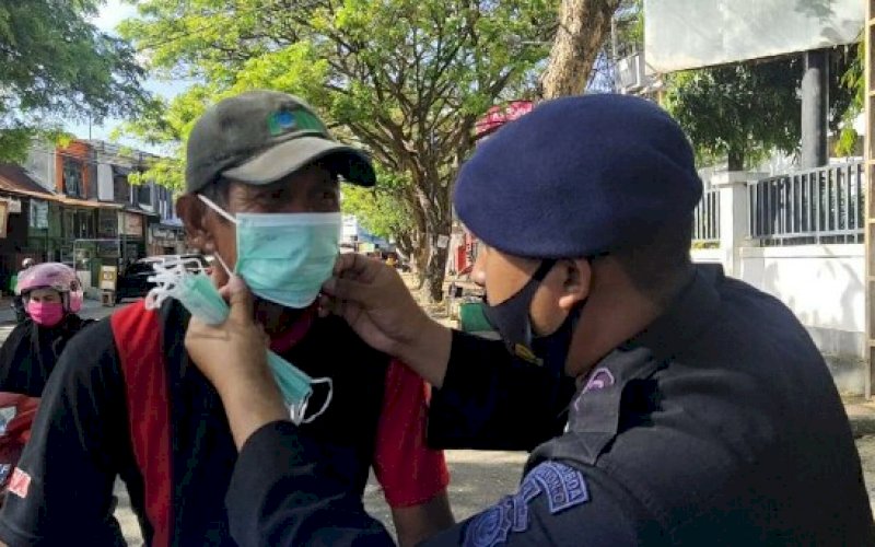 PASANGKAN MASKER. Personel Batalyon C Pelopor Satbrimob Polda Sulsel memasangkan masker kepada warga di Kabupaten Bone, Jumat (25/9/2020). foto: istimewa