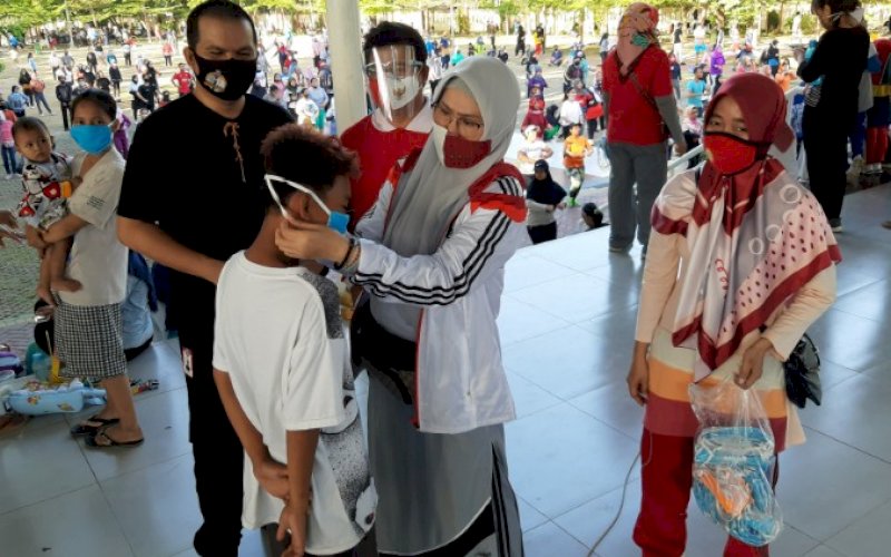 PASANGKAN MASKER. Rektor Universitas Islam Makassar (UIM), Dr Ir Hj A Majdah M Zain MSi, memasangkan masker kepada salah satu pengunjung Taman Pakui Sayang Kompleks Dinas Pekerjaan Umum Provinsi Sulsel, Jl AP Pettarani, Makassar, Minggu (6/9/2020). foto: doelbeckz/pluz.id
