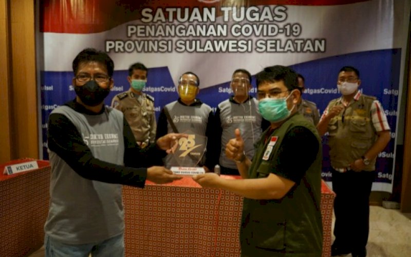 PENYERAHAN PLAKAT. Ketua Program Studi Doktor Ilmu Ekonomi FEB Unhas Makassar, Dr Anas Iswanto SE MA (kiri) menyerahkan plakat kepada tim Satuan Tugas Penanganan Covid-19 Provinsi Sulsel di Swiss-Belhotel Makassar, Sabtu (10/10/2020). foto: doelbeckz/pluz.id