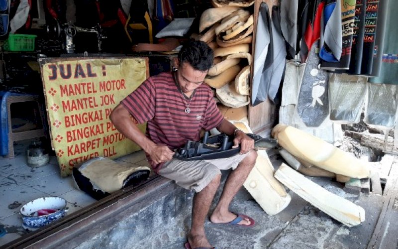 REPARASI JOK. Awal sedang mengganti gabus sekaligus pembungkus jok motor salah satu konsumennya, Rabu (28/10/2020). foto: doelbeckz/pluz.id