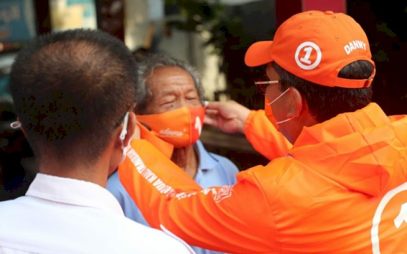 PASANGKAN MASKER. Calon Wali Kota Makassar, Moh Ramdhan Pomanto, memasangkan masker kepada salah satu warga di Kampung Rama, Kelurahan Tello Baru, Kecamatan Panakkukang, Makassar, Kamis (19/11/2020). foto: istimewa