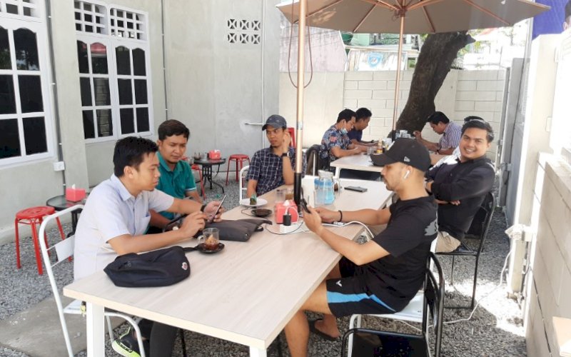 SEKETIKA. Owner Kedai Kopi Seketika, Fachrul Rays AR (kanan) dengan ramah menemani pengunjung di bagian outdoor yang teduh di bawah payung dan pohon, Kamis (12/11/2020). foto: doelbeckz/pluz.id