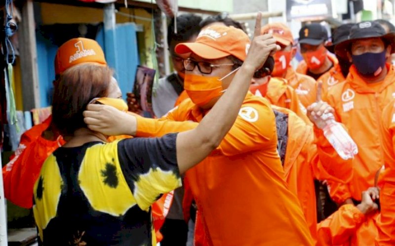 Ramdhan Pomanto, memasangkan masker kepada salah satu warga di sela-sela kampanye, belum lama ini. Menjelang pencoblosan Pilwalkot Makassar, 9 Desember 2020, Danny Pomanto kembali dilapor kubu rival ke Kepolisian. foto: istimewa