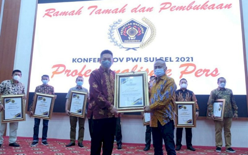 TERIMA PENGHARGAAN. Komisaris PT Baji Pamai Supermarket dan Kafe, Ivan Surianto David Tranku (kiri), menerima penghargaan berupa Gold Achievement yang diberikan PWI Sulsel dalam gelaran Konferprov PWI Sulsel 2021 di Hotel Gammara, Kota Makassar, Sulsel, Minggu (31/1/2021). foto: istimewa