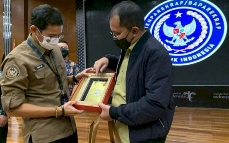 CENDERA MATA. Wali Kota Makassar Moh Ramdhan Pomanto memberikan cendera mata kepada Menteri Pariwisata dan Ekonomi Kreatif RI Sandiaga S Uno di Jakarta, Rabu (14/4/2021). foto: humas pemkot makassar