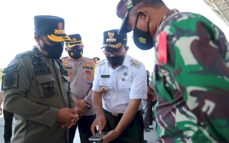 JELANG LEBARAN. Wali Kota Makassar Moh Ramdhan Pomanto (tengah) memperlihatkan data di smartphone miliknya kepada Plt Gubernur Sulsel Andi Sudirman Sulaiman (kiri) di sela-sela apel gelar pasukan dalam rangka Operasi Ketupat 2021 Pengamanan Hari Raya Idulfitri 1442 H yang diadakan Polrestabes Makassar di Lapangan Karebosi, Rabu (5/5/2021). foto: humas pemkot makassar