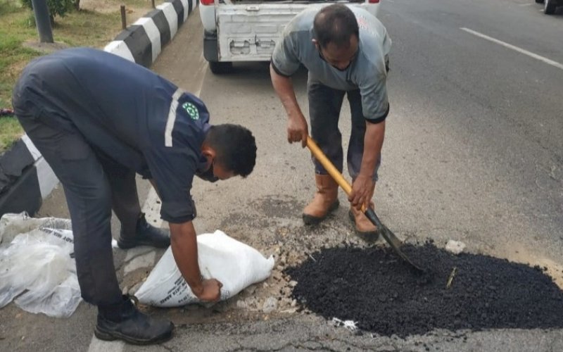 PENAMBALAN. Pekerja melakukan penambalan jalan berlubang di Jl Penghibur, Kota Makassar, yang diinisiasi Makassar Cycling Club (MCC), Rabu (5/5/2021). foto: humas mcc