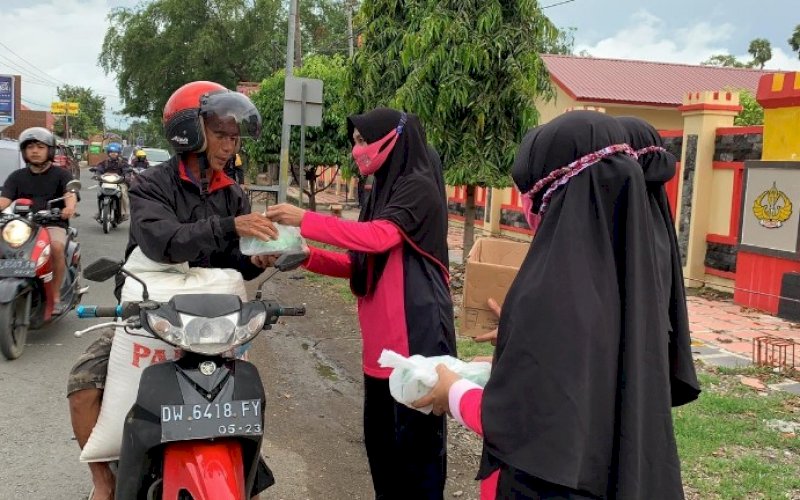 BERBAGI TAKJIL. Anggota Bhayangkari Ranting Batalyon C Pelopor membagikan takjil kepada pengendara motor, Kamis (6/5/2021). foto: humas brimob bone