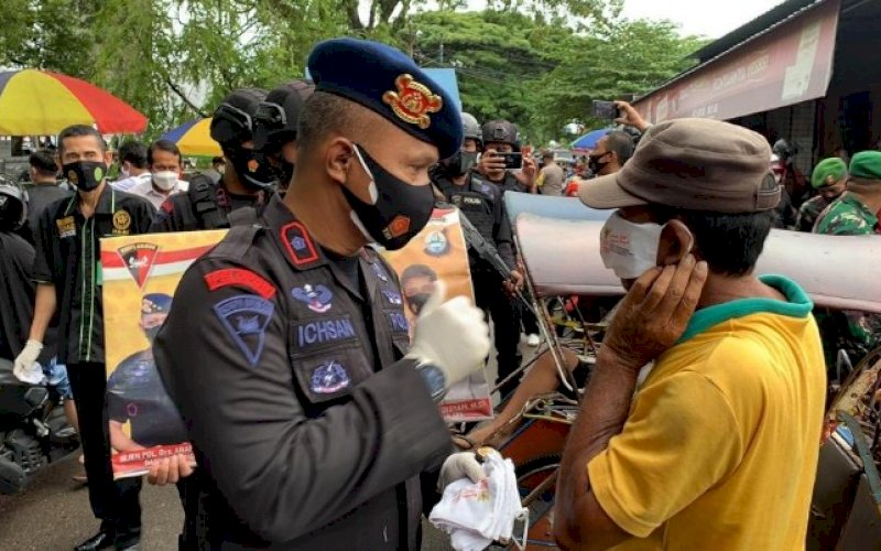BAGI MASKER. Danyon C Pelopor Satbrimob Polda Sulsel, Kompol Nur Ichsan, turun langsung membagikan dan memasangkan masker kepada warga di Bone, Jumat (9/7/2021). foto: istimewa