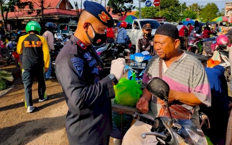 BAGI MASKER. Danyon C Pelopor Satbrimob Polda Sulsel, Kompol Nur Ichsan, bagi-bagi masker di lokasi pasar tradisional Palakka, Kelurahan Bulu Tempe, Kecamatan Tanete Riattang Barat, Bone, Minggu (18/7/2021). foto: istimewa
