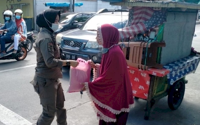 BAGI SEMBAKO. Petugas Satpol PP Kota Makassar mendistribusikan paket bahan pokok (sembako) bagi warga yang berdampak pada perekonomiannya akibat pandemi Covid-19. foto: istimewa