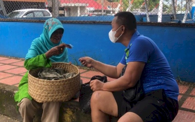 PEDULI. Danyon C Pelopor Satbrimob Polda Sulsel, Kompol Nur Ichsan, memborong jualan seorang nenek tua yang tengah beristirahat dengan membawa bakul yang masih penuh barang dagangan di pinggir trotoar dekat Gelanggang Olahraga Lapangan Merdeka Watampone, Bone, Selasa (27/7/2021). foto: istimewa