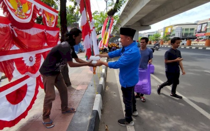 KNPI BERBAGI. Ketua DPD II KNPI Makassar, Hasrul Kaharuddin, membagikan nasi dos kepada warga dan pengguna jalan di Jl AP Pettarani, Kota Makassar, Jumat, (30/7/2021). foto: istimewa