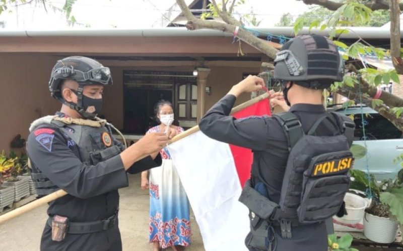 PASANG BENDERA. Tim patroli KRYD Batalyon C Pelopor Satbrimob Polda Sulsel menyambangi dan memasang bendera Merah Putih di rumah salah satu warga di Bone, Sabtu (7/8/2021). foto: istimewa