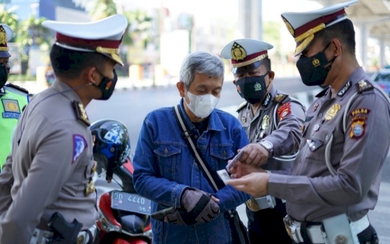 PEMERIKSAAN. Personel Ditlantas Polda Sulsel&nbsp;memeriksa kelengkapan kendaraan seorang pengendara motor di Jl Urip Sumoharjo tepatnya di bawah jembatan Flyover Makassar, Selasa (10/8/2021). foto: istimewa