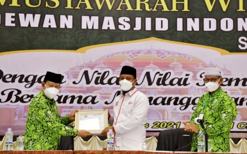 SINERGI. Ketua DMI Sulsel HM Amin Syam (kiri) menyerahkan piagam kepada Plt Gubernur Sulsel Andi Sudirman Sulaiman saat membuka kegiatan Muswil DMI Sulsel di Hotel Claro Makassar, Sabtu (14/8/2021). foto: istimewa