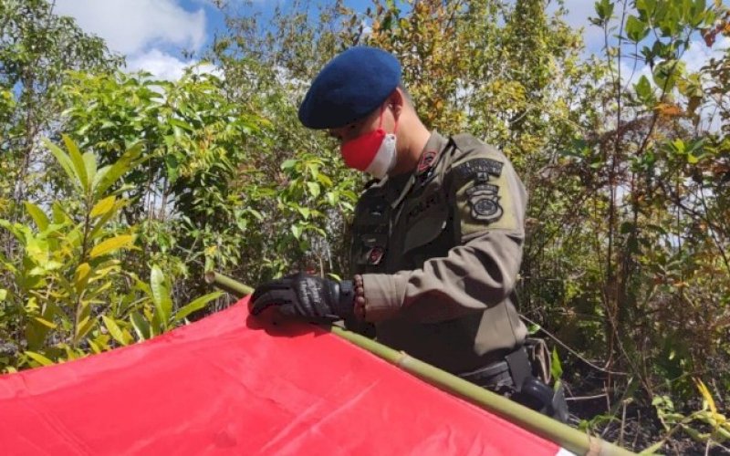 MENGIKAT BENDERA. Danyon C Pelopor Satbrimob Polda Sulsel, Kompol Nur Ichsan, mengikat bendera persiapan pengibaran bendera Merah Putih di puncak Gunung Lampoko, Bone, Senin (16/8/2021). foto: istimewa