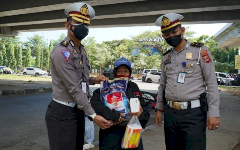 AKSI PEDULI. Kasi BPKB Ditlantas Polda Sulsel, Kompol Mamat Rahmat (kiri) mendatangi membeli tisu dan menyerahkan bantuan sembako kepada pedagang di bawah jembatan Flyover Makassar, Jl Urip Sumoharjo, Jumat (20/8/2021). foto: istimewa