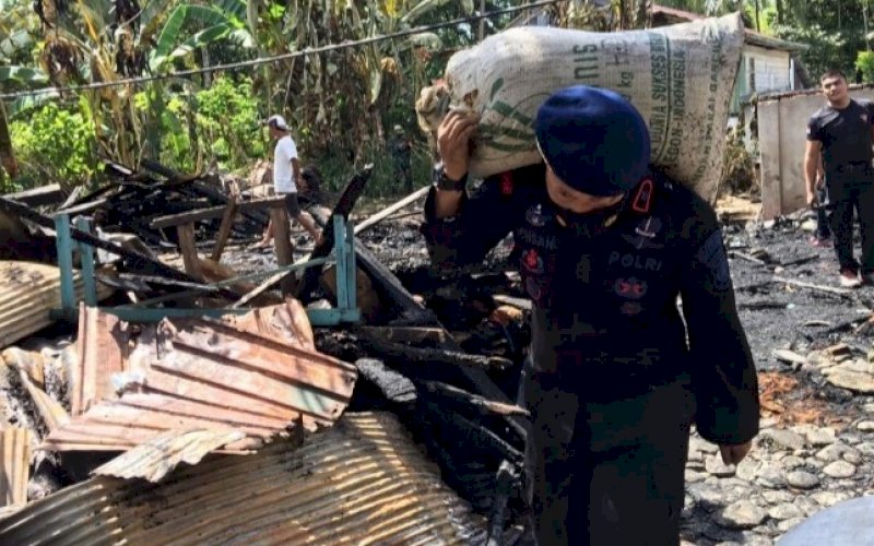 MEMIKUL. Danyon C Pelopor Sat Brimob Polda Sulsel, Kompol Nur Ichsan, memikul puing-puing kebakaran saat melakukan pembersihan, Sabtu (21/8/2021). foto: istimewa