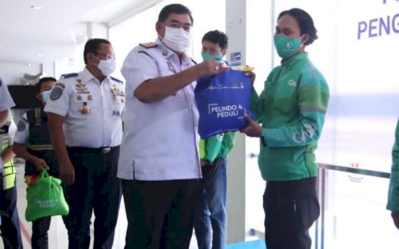 SERAHKAN BINGKISAN. Sekda Provinsi Sulsel, Abdul Hayat Gani, menyerahkan bingkisan kepada peserta vaksinasi pengemudi transportasi online dan pengemudi truk di Area Pelabuhan Makassar yang dilaksanakan di Aula Kantor Pelindo IV, Rabu (25/8/2021). foto: istimewa