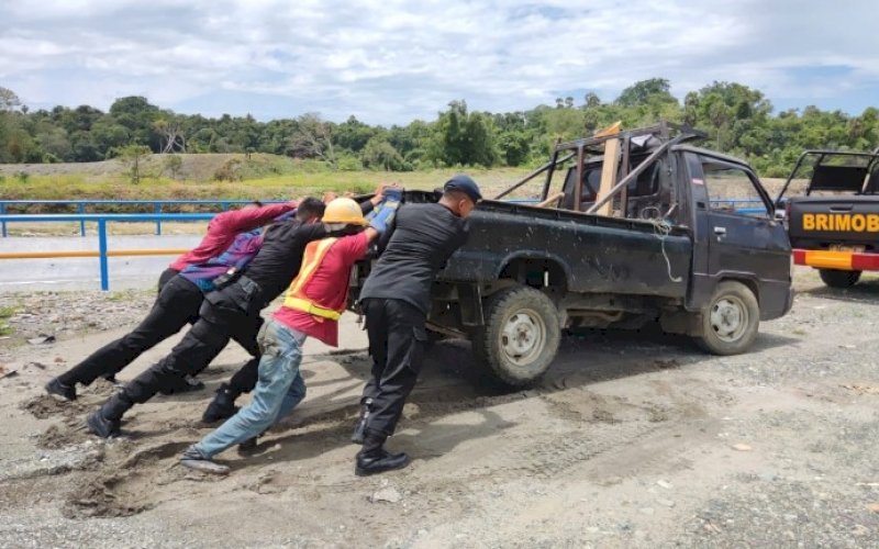 EVAKUASI. Danyon C Pelopor Satbrimob Polda Sulsel, Kompol Nur Ichsan, turun langsung membantu mengevakuasi mobil pickup yang terjebak lumpur, Rabu (8/9/2021). foto: istimewa