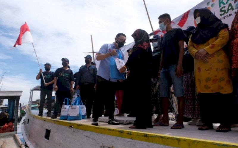 BAGI SEMBAKO. Relawan Kawan Sandi, Andre Arief Bulu, membagikan paket aksi sosial di sela-sela deklarasi Calon Presiden Sandiaga Salahuddin Uno di atas Kapal Perahu Rakyat Paotere Kota Makassar, Rabu (15/9/2021). foto: istimewa