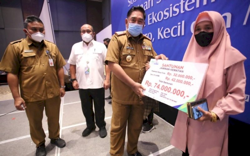 SANTUNAN. Sekda Provinsi Sulsel, Abdul Hayat Gani, menyerahkan santunan BPJS Ketenagakerjaan kepada penerima di Four Points by Sheraton Makassar, Selasa (5/10/2021). foto: istimewa