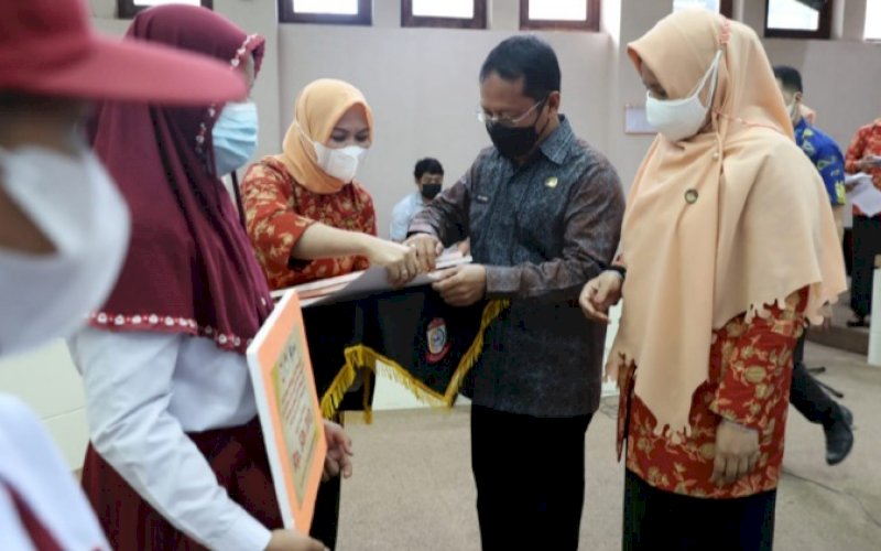 PENYERAHAN. Sekda Kota Makassar yang juga selalu Penasihat DWP Kota Makassar, Muh Ansar, menyerahkan bantuan pendidikan bagi anak ASN Golongan I dan Golongan II yang berprestasi tingkat SD dan SMP di Ruang Sipakatau Lt 2 Kantor Balai Kota Makassar, Jumat (15/10/2021). foto: istimewa