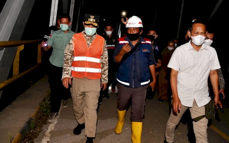PENINJAUAN. Plt Gubernur Sulsel, Andi Sudirman Sulaiman (kiri), meninjau kondisi jembatan Sungai Battang yang menjadi akses Kota Palopo-Kabupaten Luwu yang mengalami keretakan dan miring akibat tergerus arus&nbsp; sungai yang meluap, sekitar pukul 22.00 WITA, Selasa (9/11/2021). foto: istimewa