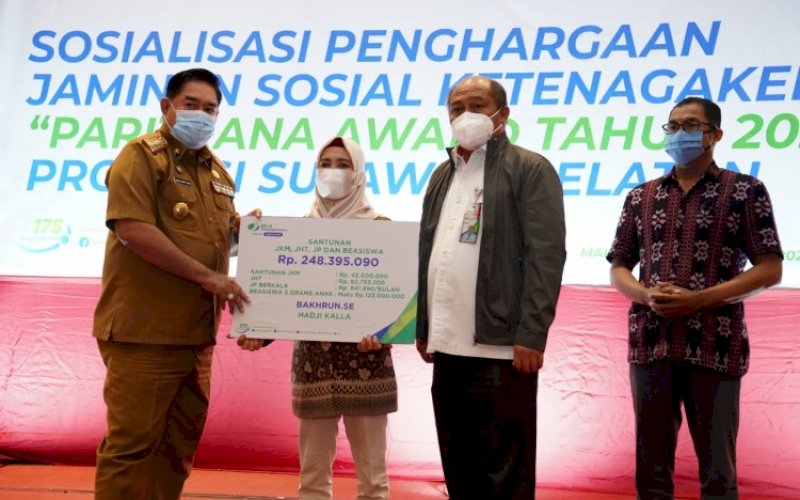 BERI SANTUNAN. Sekda Provinsi Sulsel Abdul Hayat Gani disaksikan Deputi Direktur BPJS Ketenagakerjaan Wilayah Sulawesi Maluku Arif Budiarto menyerahkan santunan secara simbolis kepada peserta BPJS Ketenagakerjaan di Hotel Gammara Makassar, Selasa (28/12/2021). foto: istimewa
