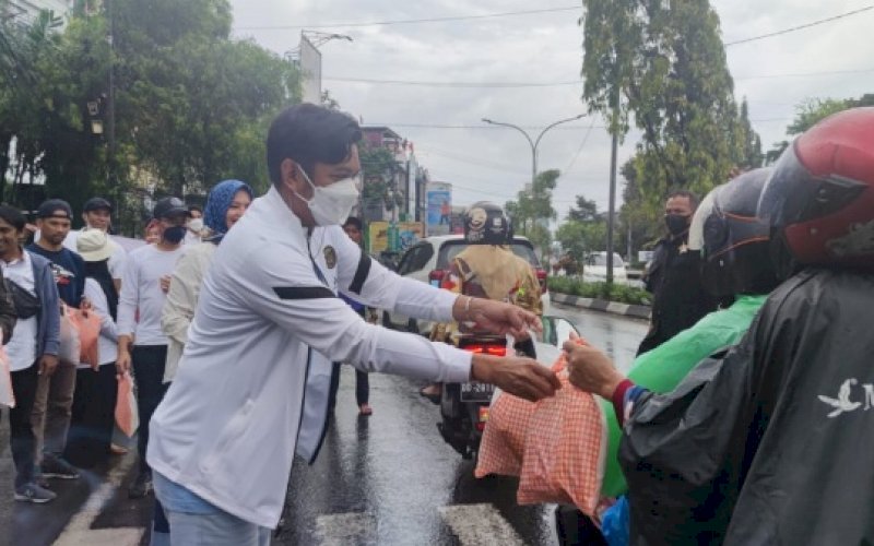 BERBAGI. Kepala Bapenda Kota Makassar, Firman Hamid Pagarra, membagikan makanan rebus kepada pengguna jalan dalam rangka memeriahkan Festival Rebus Makassar, Minggu (27/3/2022). foto: istimewa