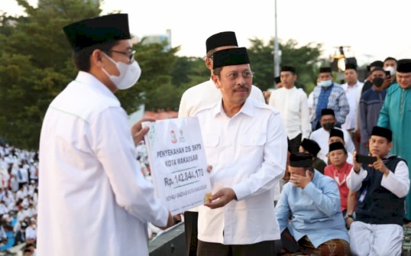 PENYERAHAN ZAKAT. Sekda Kota Makassar Muh Ansar (kanan) menyerahkan zakat ASN Pemkot Makassar kepada Wali Kota Makassar&nbsp;Moh Ramdhan Pomanto yang selanjutnya diberikan ke Baznas di sela-sela Salat Subuh berjemaah di pelataran City of Makassar, Anjungan Pantai Losari Makassar, Minggu (24/4/2022). foto: istimewa