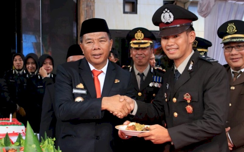 PENYERAHAN TUMPENG. Bupati Bulukumba, Andi Muchtar Ali Yusuf, memotong tumpeng dan menyerahkan kepada personel Bintara termuda Polres Bulukumba di sela-sela upacara peringatan Hari Bhayangkara Ke-76 di Lapangan Apel Mapolres Bulukumba, Selasa (5/7/2022). foto: istimewa