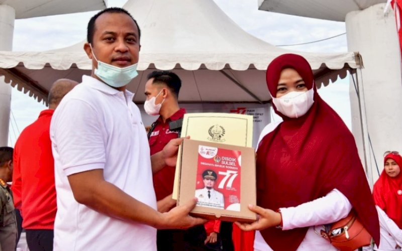 PENYERAHAN. Gubernur Sulsel, Andi Sudirman Sulaiman, menyerahkan bantuan beasiswa UPZ Baznas Pemprov Sulsel pada acara jalan sehat Gerakan Sulsel Anti Mager di Kawasan Center Point of Indonesia (CPI) Makassar, Jumat (12/8/2022). foto: istimewa