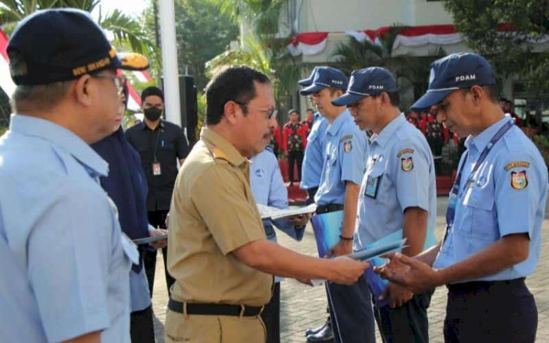 PENGHARGAAN. Sekda Kota Makassar Muh Ansar didampingi Direktur Utama Perumda Air Minum Kota Makassar Beni Iskandar menyerahkan penghargaan kepada karyawan Perumda Air Minum Kota Makassar saat upacara bersama seluruh karyawan dalam rangka memperingati HUT ke-98 di Lapangan Upacara Perumda Air Minum Kota Makassar, Senin (8/8/2022). foto: istimewa