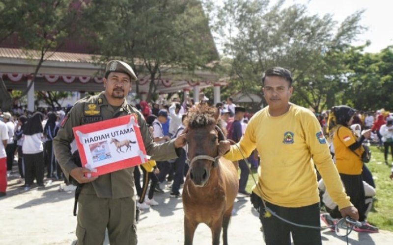 HADIAH. Petugas Satpol PP Kabupaten Jeneponto, Mukhtar, menerima hadiah utama jalan sehat Sulsel Anti Mager di Kabupaten Jeneponto, Selasa (25/10/2022). foto: istimewa