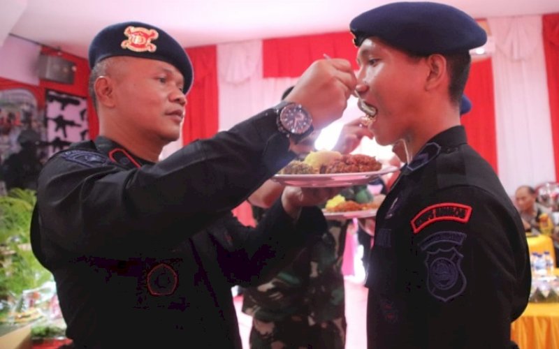 SYUKURAN. Danyon C Pelopor Satbrimob Polda Sulsel, Kompol Nur Ichsan, menyuap nasi tumpeng kepada salah seorang personel Batalyon C Pelopor Satbrimob Polda Sulsel sebagai tanda syukuran HUT Korps Brimob Polri Ke-77, 14 November 2022 di Aula Mako Batalyon C Pelopor, Kabupaten Bone, Jumat (18/11/2022). foto: istimewa