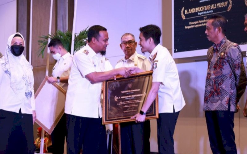 PENGHARGAAN. Gubernur Provinsi Sulsel Andi Sudirman Sulaiman menyerahkan penghargaan kepada Kepala Disdukcapil Kota Makassar Muhammad Hatim dalam acara 'Penghargaan Pencapaian Disdukcapil Provinsi Sulsel' yang digelar di Hotel Claro Makassar, Rabu (14/12/2022). foto: istimewa