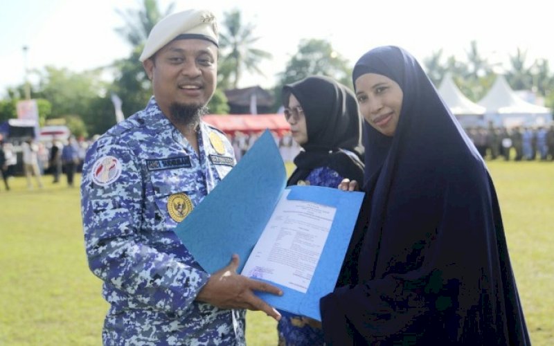 PENYERAHAN. Gubernur Sulsel, Andi Sudirman Sulaiman, menyerahkan SK sebanyak 1.239 orang pengangkatan PPPK jabatan fungsional guru tahap II Formasi Tahun Anggaran 2021 pada Upacara Hari Bela Negara Ke-74 di Lapangan Latemmupage, Desa Bulue, Kabupaten&nbsp; Soppeng, Senin (19/12/2022). foto: istimewa