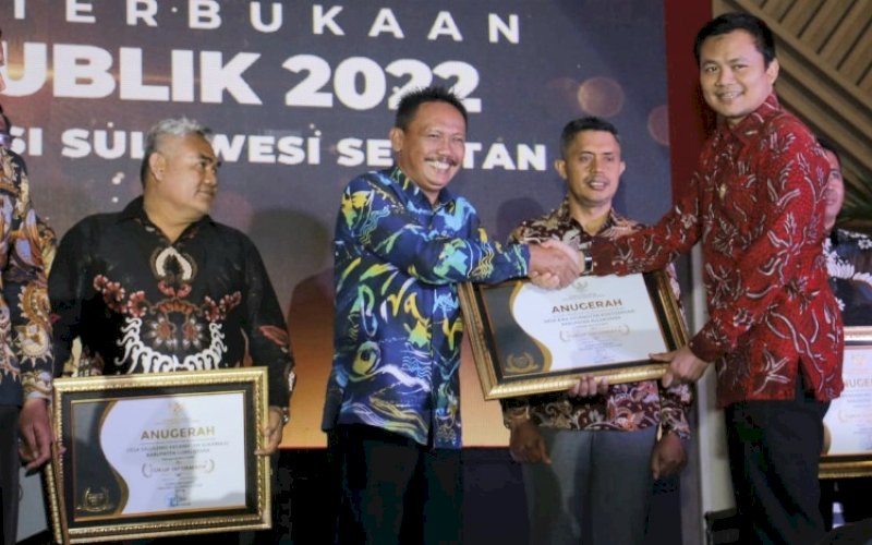 PENGHARGAAN. Kepala Desa Bira Murlawa yang diserahkan Wakil Ketua KI Pusat Arya Sandhiyudha pada acara Penganugerahan Keterbukaan Informasi Publik, yang berlangsung di Ballroom Sandeq Hotel Claro Makassar, Jumat (2/12/2022) malam. foto: istimewa