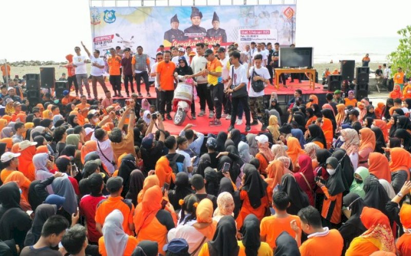 PENYERAHAN HADIAH. Gubernur Sulsel Andi Sudirman Sulaiman didampingi Bupati Bulukumba Andi Muchtar Ali Yusuf menyerahkan hadiah utama motor kepada pemenang jalan sehat Sulsel Anti Mager di Pantai Merpati Bulukumba, Minggu (5/2/2023). foto: istimewa