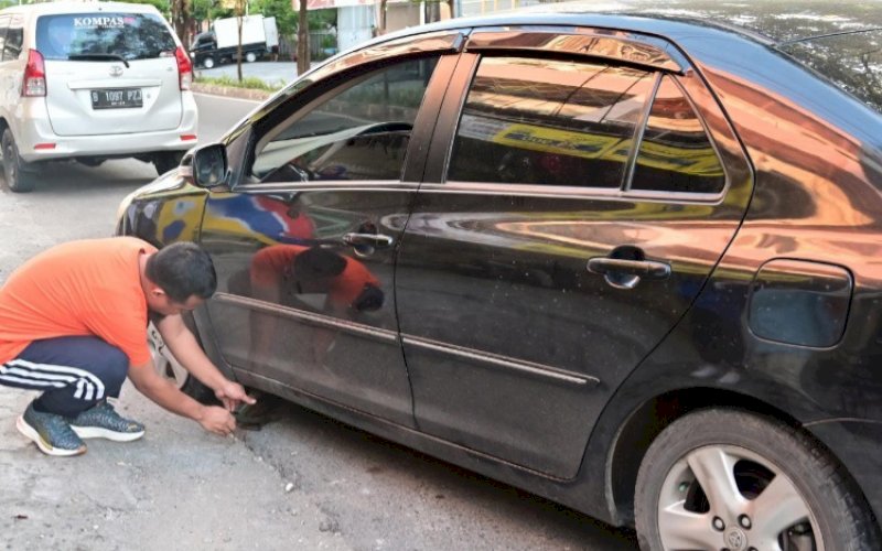 MEMBANTU. Gubernur Sulsel, Andi Sudirman Sulaiman, membantu memperbaiki ban bocor mobil seorang ibu yang dijumpai di jalan, Minggu (12/3/2022). foto: istimewa
