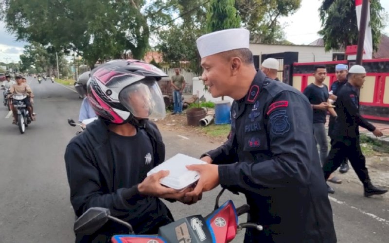 BERBAGI. Danyon C Pelopor Sat Brimob Polda Sulsel, Kompol Nur Ichsan, y.ang memimpin langsung aksi bagi paket takjil dan makanan siap saji kepada pengguna jalan di Watampone, Kabupaten Bone, Senin (3/4/2023). foto: istimewa
